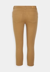 Pantalones de color marrón claro, ajustados y vistos desde atrás, hechos de tela elástica. Presentan dos bolsillos traseros y una cintura de altura media.