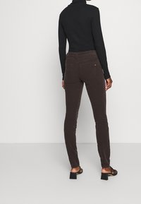 Bruine corduroy broek met een slim fit, met een middelhoog taille en achterzakken, gecombineerd met een zwarte longsleeve top en hakken.