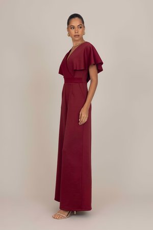 Combinaison bourgogne avec un décolleté en V profond, des manches courtes à volants, une taille cintrée et un pantalon à jambes larges. Fabriquée en tissu épais sans motifs.