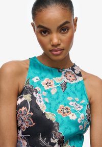 Sukienka na halter w turkusowo-czarny wzór kwiatowy. Wykonana z gładkiego materiału z misternymi detalami kwiatowymi i eleganckimi teksturami.