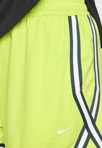 Neon grønne sportsshorts med struktureret stof, elastisk talje og kontrasterende mørkegrå og hvide striber på siderne.