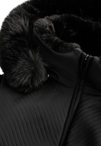 Czarna kurtka z pikowanym wzorem, sztucznym futrem przy kołnierzu oraz zamkiem z przodu. Gładka tekstura z pluszowym wykończeniem kołnierza.