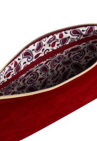 Rode fluwelen clutch met gouden rits, met een paisley-gepatroneerde stofvoering in rood, marineblauw en wit aan de binnenkant. Twee compartmenten zichtbaar.