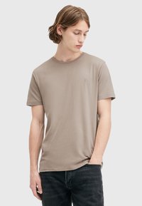 T-shirt a maniche corte, con collo girocollo in taupe caratterizzato da una texture di cotone liscia. Presenta un ricamo del logo discreto sul petto e una vestibilità rilassata.