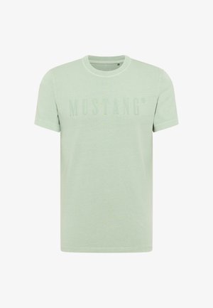 Hellgrünes Baumwoll-T-Shirt mit kurzen Ärmeln, ausgestattet mit einem strukturierten "MUSTANG"-Logo über der Brust. Reguläre Passform mit Rundhalsausschnitt.