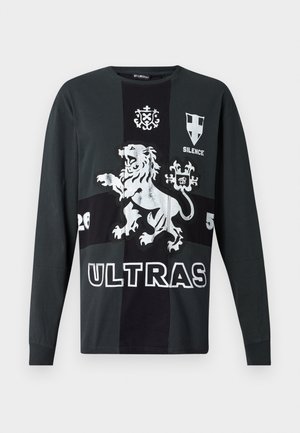 Garais piedurknes melns T-krekls ar sudraba lauva grafiku, tekstu "ULTRAS" un dažādiem dizainiem. Izgatavots no mīksta kokvilnas materiāla.