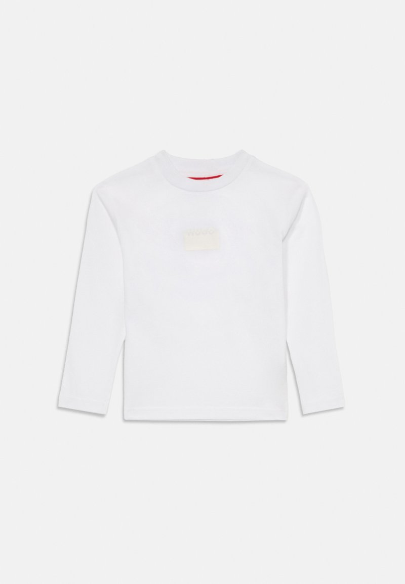 T-shirt branco de manga longa em algodão. Apresenta um decote redondo e um pequeno emblema quadrado na frente em bege. Textura suave.