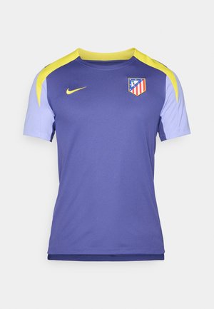Jersey de manga corta en púrpura y azul claro, hecho de tela transpirable, con un detalle amarillo en el hombro y un logo del equipo en el pecho.