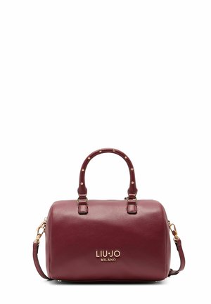 Sac à main en cuir bordeaux avec doubles poignées, accents dorés et bandoulière amovible. Présente une texture granuleuse et le logo de la marque sur le devant.