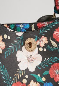 Sac en tissu noir avec un imprimé floral multicolore, doté d'un fermoir circulaire doré à torsion gravé du texte "icredi".