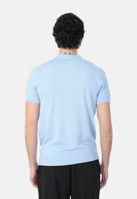 Polo shirt azzurro chiaro a maniche corte con colletto e polsini a costine, caratterizzato da una vestibilità regolare e una superficie liscia. Nessun motivo o decorazione visibili.