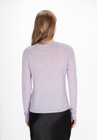 Tricou cu mâneci lungi în lavandă deschis, cu o textură netedă și decolteu rotund. Prezintă mâneci ajustate și un tiv ușor curbat.