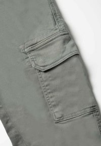 Cargo broek in een gedempt grijze stof, met een grote zak aan de zijkant, platte naden en een gladde, licht gestructureerde uitstraling.