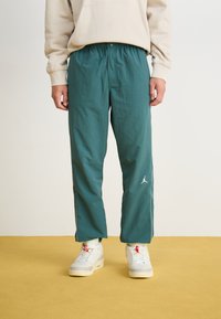 Teal, loszittende joggers met een elastische tailleband. Kenmerkt zich door het witte Jordan-logo aan de linkerkant en subtiele zijstrepen.