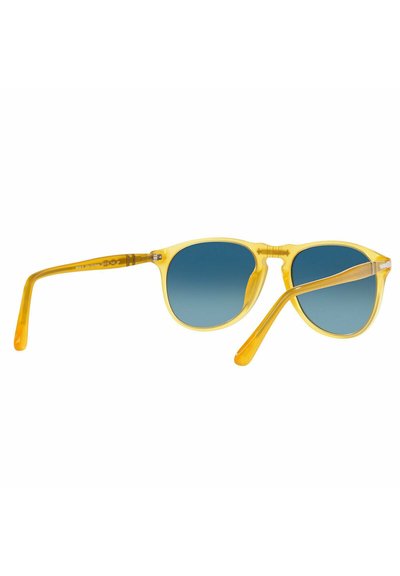 Occhiali da sole gialli in plastica con lenti blu a gradiente, montatura rotonda e astine testurizzate. Accenti trasparenti esaltano il design.