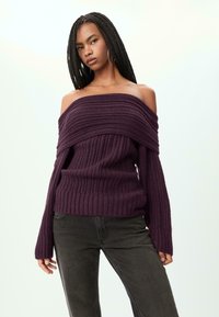 Violetti off-the-shoulder ribbipusero pitkille hihoille ja leveälle käänteelle, yhdistettynä tummanharmaisiin farkkuihin. Teksturoitu neulekangas.