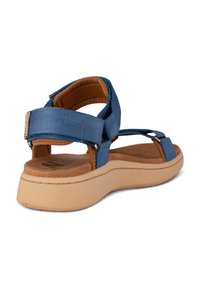 Blue sandal with soft fabric straps and beige rubber sole. Features cushioned footbed, adjustable strap, and minimal stitching details.