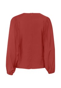 Blouse rouge à manches longues avec épaules bouffantes froncées, poignets élastiques et fermeture éclair au dos.