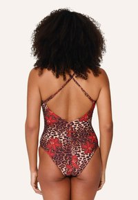 Maillot de bain de una pieza con estampado de leopardo y acentos florales rojos, tirantes cruzados ajustables y diseño de espalda en V profunda.