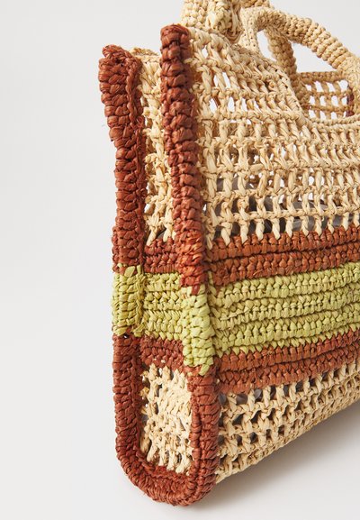 Sac en paille tissé avec des bandes de couleurs rouge, vert et naturel, présentant un motif de tissage ouvert et de petites poignées rondes.