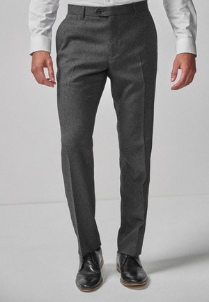 Homme portant un pantalon habillé slim-fit à carreaux gris foncé, associé à des chaussures en cuir noires et une chemise blanche.