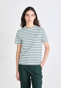 Hvit t-skjorte med grønne og marineblå horisontale striper, rund halsutskjæring, korte ermer, med en liten grønn logo på brystet.