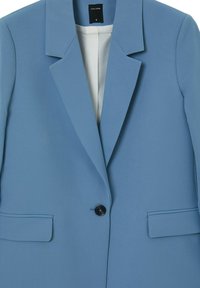 Blazer azzurro chiaro con colletto a revers, chiusura con un solo bottone nero, due tasche frontali e tessuto liscio. Interno foderato.