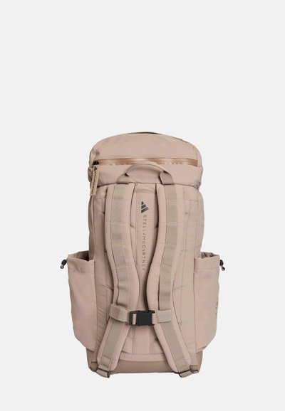 Beige backpack with padded back, dual side pockets, adjustable straps, and a zippered top. Features logo and textured fabric design.