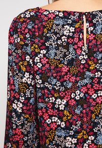 Black floral dress featuring a colorful print with small flowers in pink, white, yellow, and blue; includes a keyhole detail at the back.