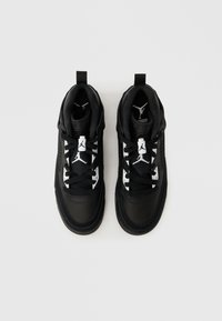 Ζευγάρι ασπρόμαυρα αθλητικά παπούτσια Air Jordan με κορδόνια, λογότυπο Jumpman στη γλώσσα και στις ταινίες στο πίσω μέρος, από πάνω σε λευκό φόντο.