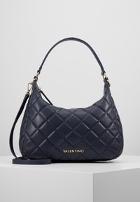 Mörkblå läderhandväska med quiltat mönster, en kort axelrem och en avtagbar lång rem; guld "VALENTINO"-logotyp på framsidan.