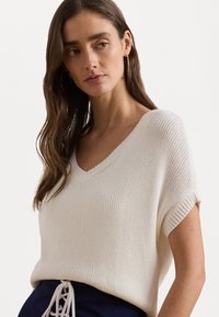 Κρεμ χρώματος, φαρδύ πλεκτό πουλόβερ με V λαιμόκοψη και κοντά μανίκια, με υφή από ραβδωτό σχέδιο.