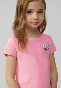 Roze katoenen T-shirt met korte mouwen, met geborduurde bloemen in blauw en wit op het linker borstgebied. Gladde textuur.