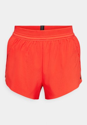 Shorts de sport rouges en tissu léger avec une taille élastique, dotés de poches latérales et d'un petit logo noir sur l'ourlet.