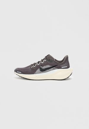 Chaussure de sport gris foncé avec une tige en mesh, des accents noirs, des détails réfléchissants et une semelle intercalaire blanche. Dotée d'une semelle extérieure en caoutchouc texturé.
