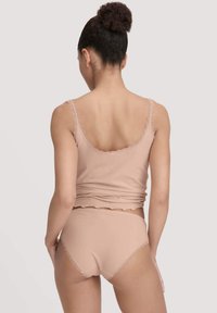 Nude tanktop en bijpassende hooggetailleerde slipjes met golvende kantdetails, gemaakt van zacht, rekbaar materiaal voor comfort.