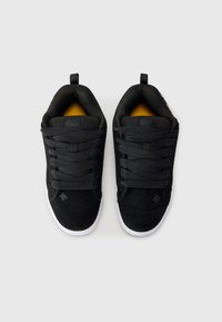 Svarte joggesko med overdel i semsket skinn, teksturerte lisser og hvit gummisåle. Gule detaljer synlige innvendig i skoen. Flat design, lavt toppstil.