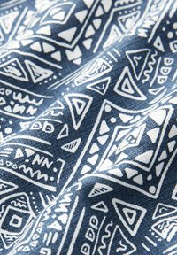 Marineblauer Stoff mit weißen geometrischen Mustern, einschließlich Dreiecken, Linien und Punkten. Die Textur scheint gewebt und leicht strukturiert zu sein.