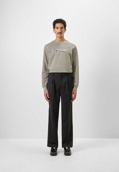 Sweatshirt gri cu mânecă lungă, dotat cu un text grafic, asortat cu pantaloni plisati negri și pantofi negri cu șireturi. Design simplu și modern.