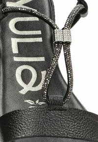 Sandal negra con una correa de cuero texturizado, acento de strass en el centro y logotipo impreso en la plantilla.