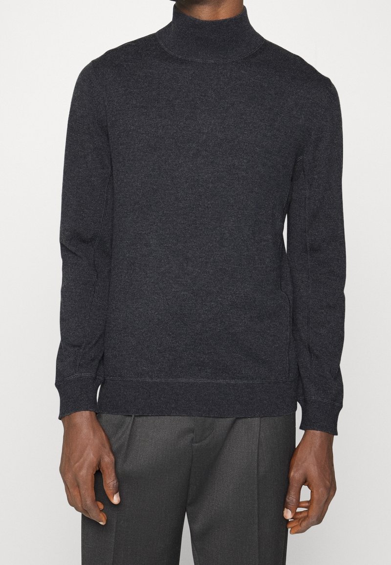 Pull en col roulé gris foncé en tissu doux et texturé ; design ajusté avec des manches longues et des poignets et un ourlet côtelés.