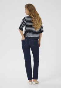 Striped navy and white short-sleeve top paired with dark blue jeans. The jeans feature rear pockets and a straight-leg cut.