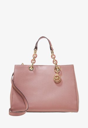 Różowa skórzana torebka z uchwytami z łańcucha w kolorze złotym i okrągłą zawieszką z logo MK, wyposażona w odpinany skórzany pasek na ramię.
