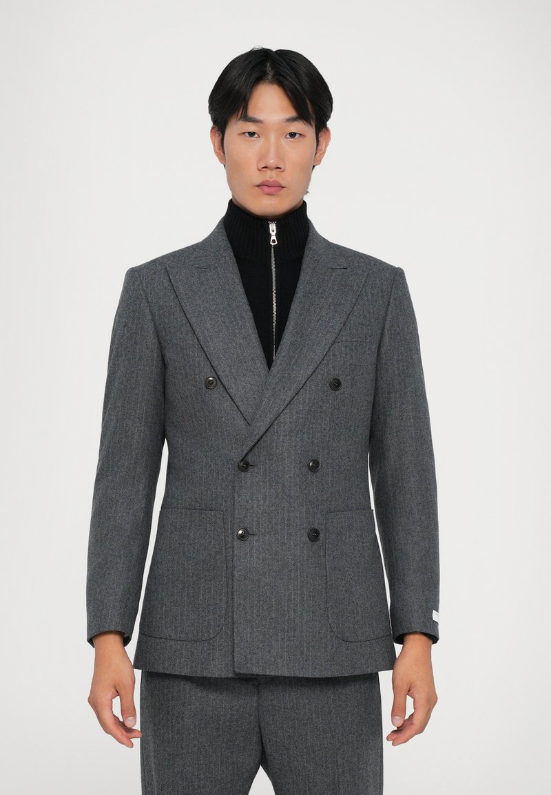 Halli kahepealne bleiser halli pinstripe mustriga, mustade nööpidega, kahe eesmise taskuga, musta tõmblukuga kõrge kaelusega sviitri peal.