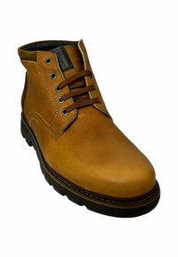 Botín de cuero marrón claro hasta el tobillo con punta redonda, acentos cosidos, seis ojales y cordones marrones. Suela de goma con agarre texturizado. Forro interior negro.