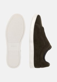 Tmavě zelené semišové slip-on tenisky s bílými gumovými podrážkami. Mají hladké a texturované panely, zaoblenou špičku a elastické boční detaily.