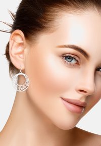 Orecchini circolari in filigrana d'argento con modelli intricati, design leggero e forma ad anello, appesi a un semplice gancio.