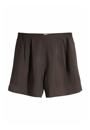 Talia i górna część nóg osoby noszącej luźne, czarne spodenki z elastycznym pasem i detalami kieszeni na tle teksturowanej, jasnoszarej ściany.