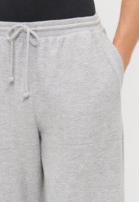 Graue Baumwoll-Sweatpants mit einem Kordelzugbund, ausgestattet mit zwei Seitentaschen und einem weichen, strukturierten Material. Entspanntes Schnittmuster und mittelhoher Bund.