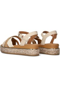 Sandali platform beige con cinturini incrociati, texture liscia e design in corda intrecciata sulla suola con una fascia metallica decorativa.